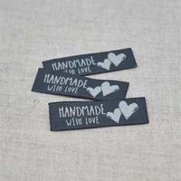 N&auml;rbild p&aring; svarta v&auml;vda etiketter med vit text "Handmade with love" och tv&aring; vita hj&auml;rtan, fr&aring;n artikeln V&auml;vd Etikett Handmade With Love Vit.